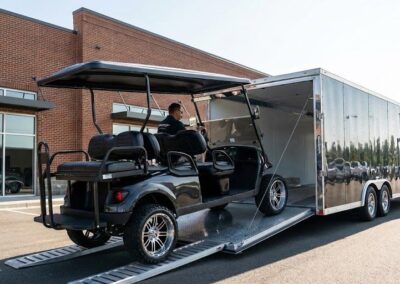A custom golf cart being loaded into a professional enclosed transport trailer.
